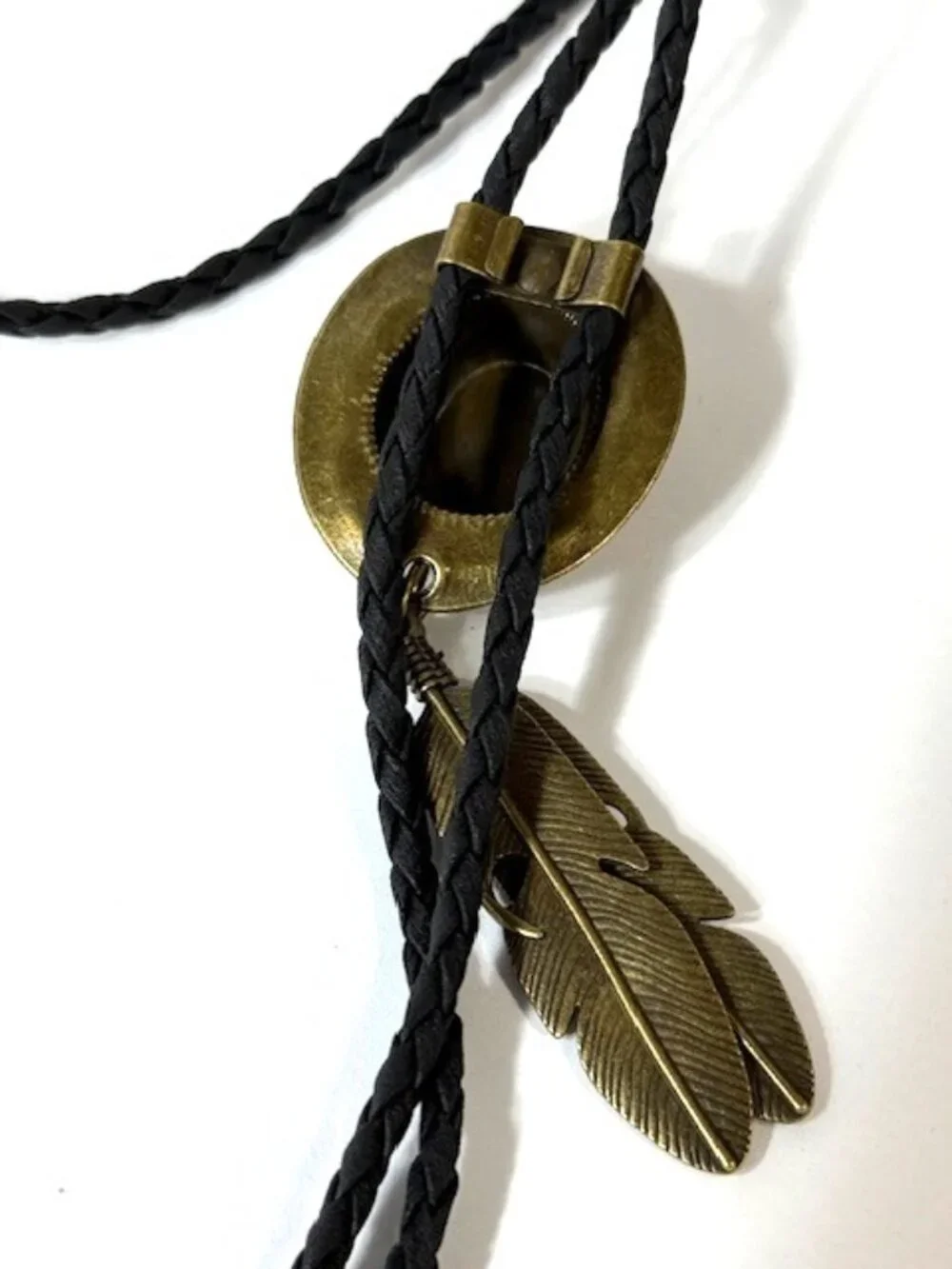 Gold-tone cowboy hat and feather, black cord western cowboy bolo tie.